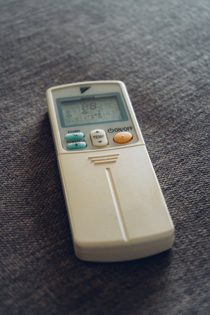 A close-up view of an air conditioner remote resting on a textured fabric surface.